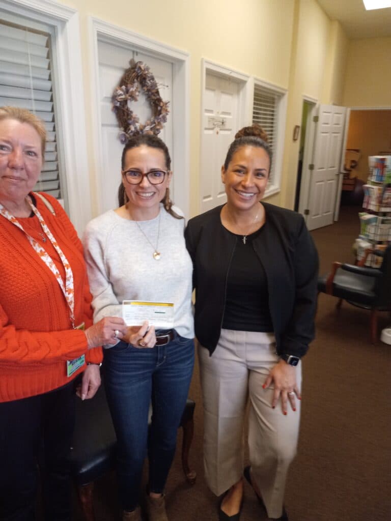 Diann makes a contribution to administrators of the Empower House domestic violence shelter.